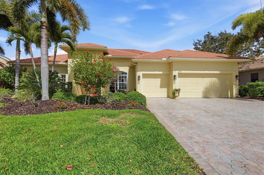 A single-story house with a tile roof, beige stucco exterior, and a paved driveway — 1251 TUSCANY BOULEVARD, VENICE, FL
