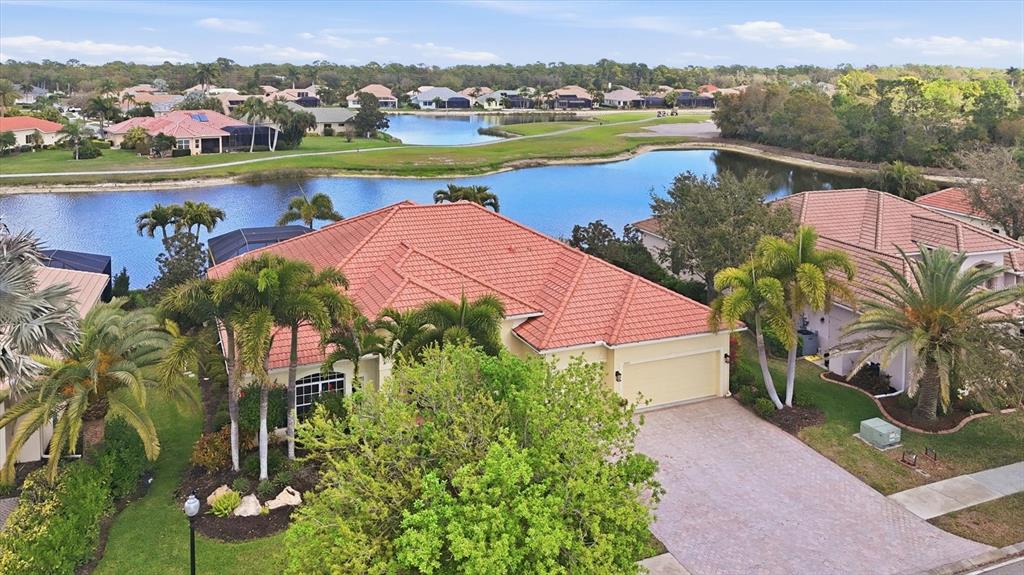 An aerial view shows a house with a red tile roof, driveway, and palm trees — 1251 TUSCANY BOULEVARD, VENICE, FL