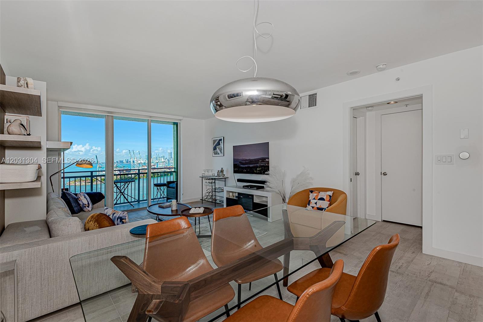 A modern living and dining area features a glass table, leather chairs, and balcony views — 90 Alton Rd # 2506, Miami Beach FL 33139, MIAMI BEACH, FL