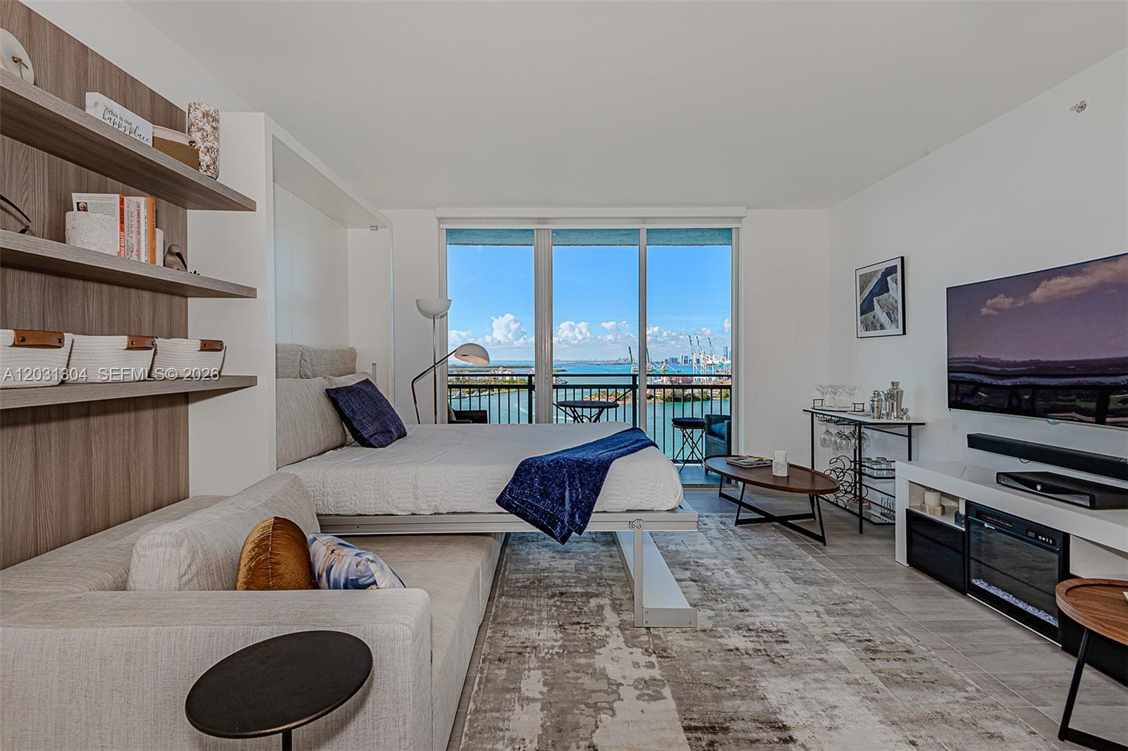 A studio apartment features a Murphy bed, a sofa, and a balcony overlooking the ocean — 90 Alton Rd # 2506, Miami Beach FL 33139, MIAMI BEACH, FL