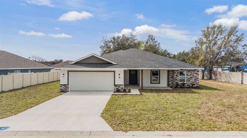 A single-story house with a white exterior, stone accents, a garage, and a concrete driveway — 38086 COUNTRYSIDE PLACE, DADE CITY, FL