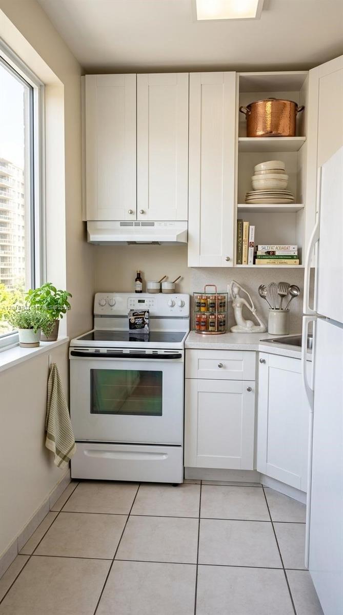 A small kitchen features white cabinets, a white electric stove, and open shelving with dishes — 666 W 81st St # 316, Hialeah FL 33014, HIALEAH, FL