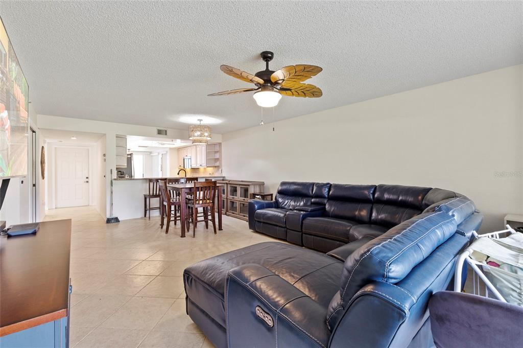 A living room features a blue leather sectional, a dining area, and a ceiling fan — 6611 STONE RIVER ROAD UNIT 102, BRADENTON, FL