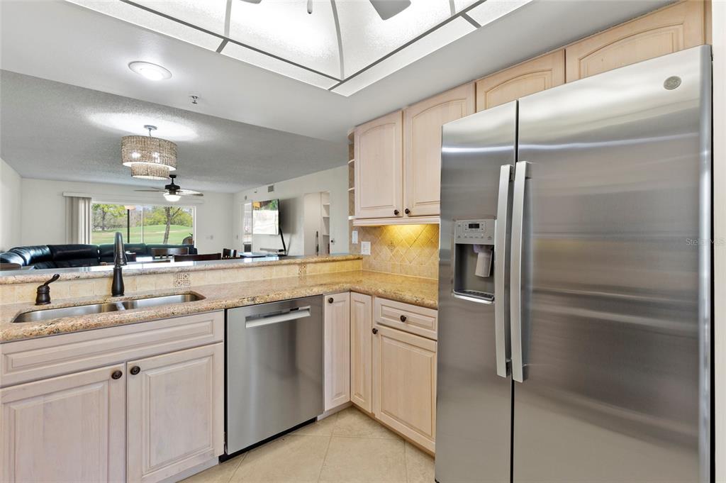 A kitchen features light wood cabinets, granite countertops, stainless steel appliances, and a breakfast bar — 6611 STONE RIVER ROAD UNIT 102, BRADENTON, FL