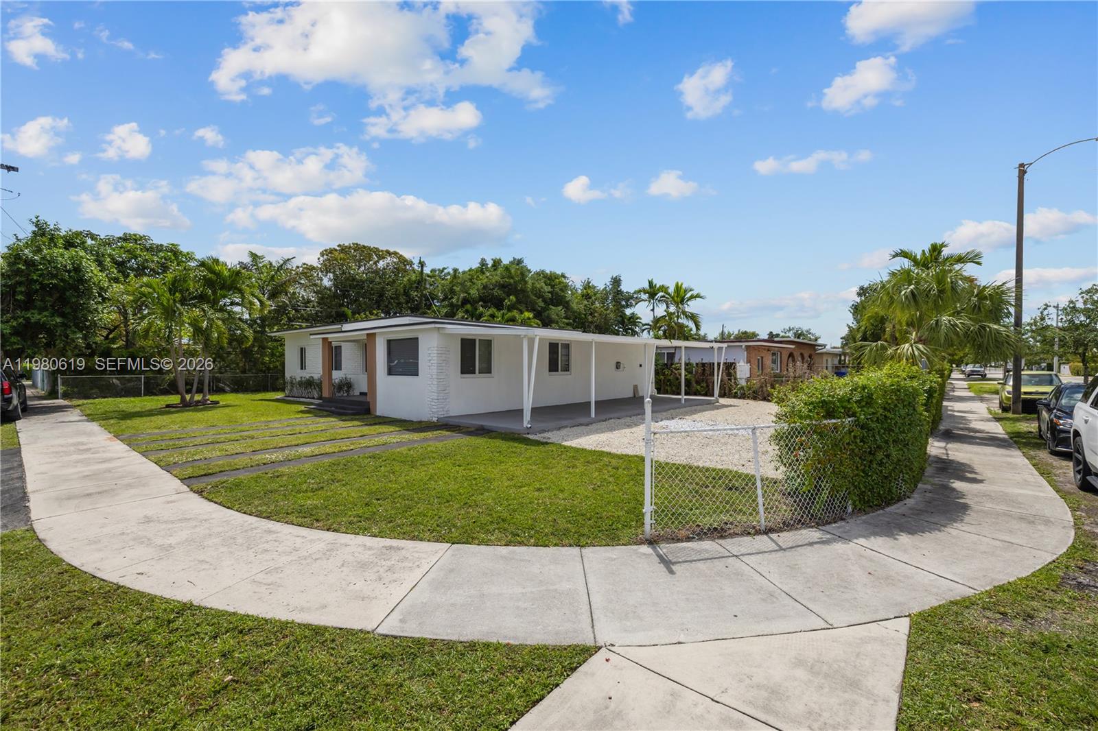 A white single-story house features a covered patio, a gravel driveway, and a chain-link fence — 5410 SW 2nd, Miami FL 33134, MIAMI, FL