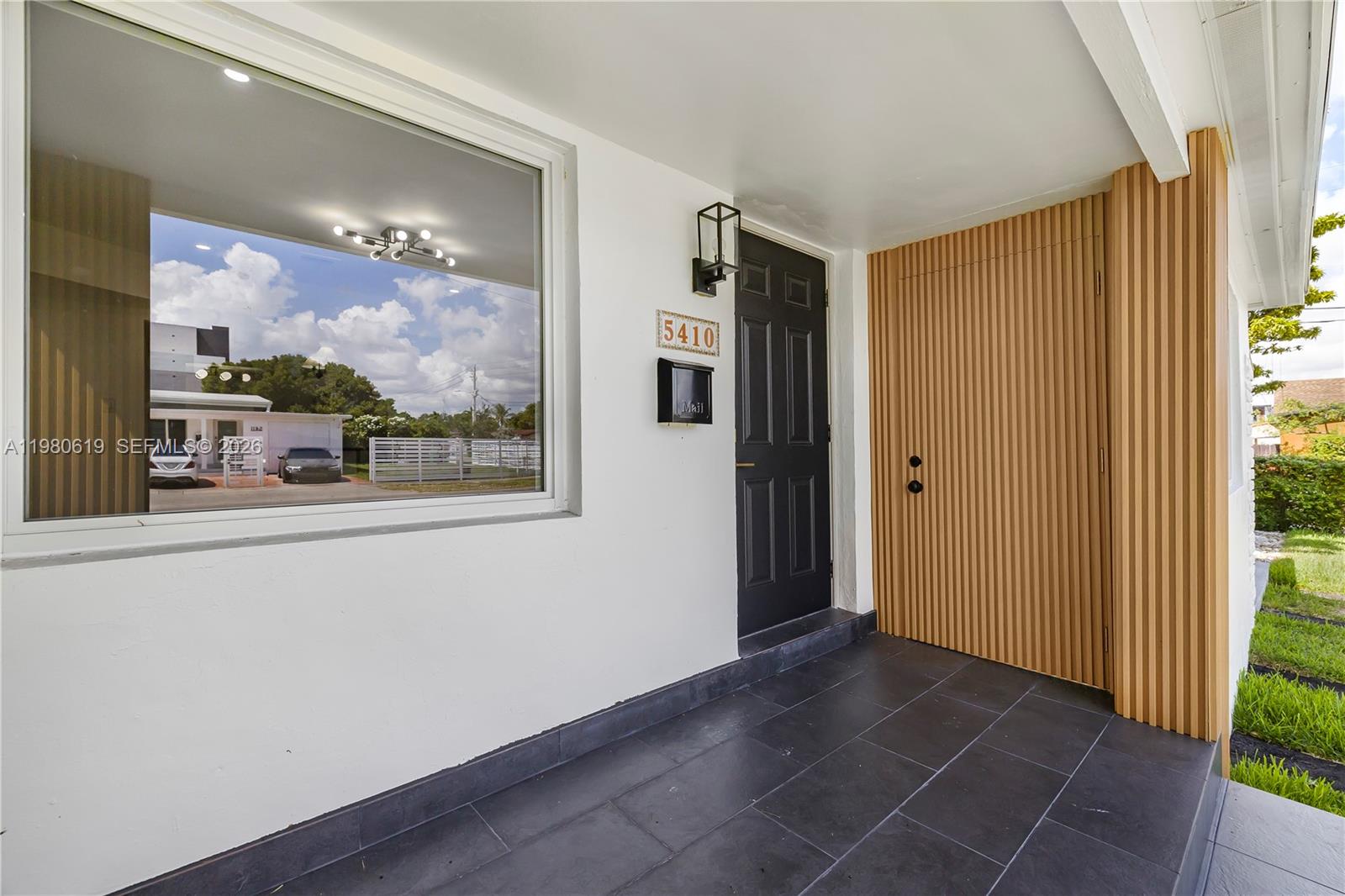 A covered porch features a black door, a large window, and a slatted wood wall — 5410 SW 2nd, Miami FL 33134, MIAMI, FL
