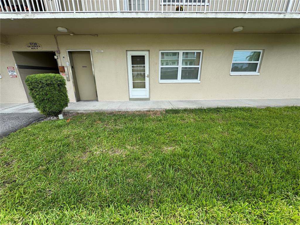 The exterior of a ground-level apartment unit features a door, a window, and a bush — 5720 13TH AVENUE N UNIT 106B, ST PETERSBURG, FL