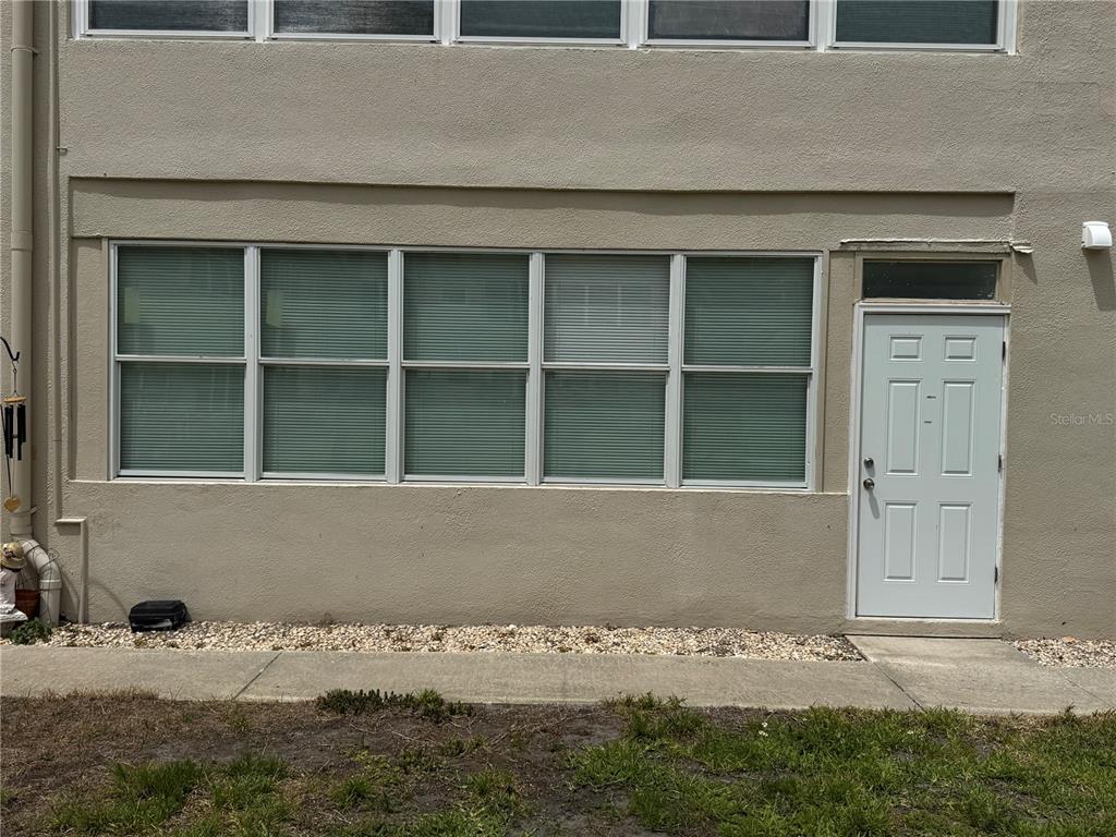 The exterior of a building features a white door and a row of large windows — 5720 13TH AVENUE N UNIT 106B, ST PETERSBURG, FL