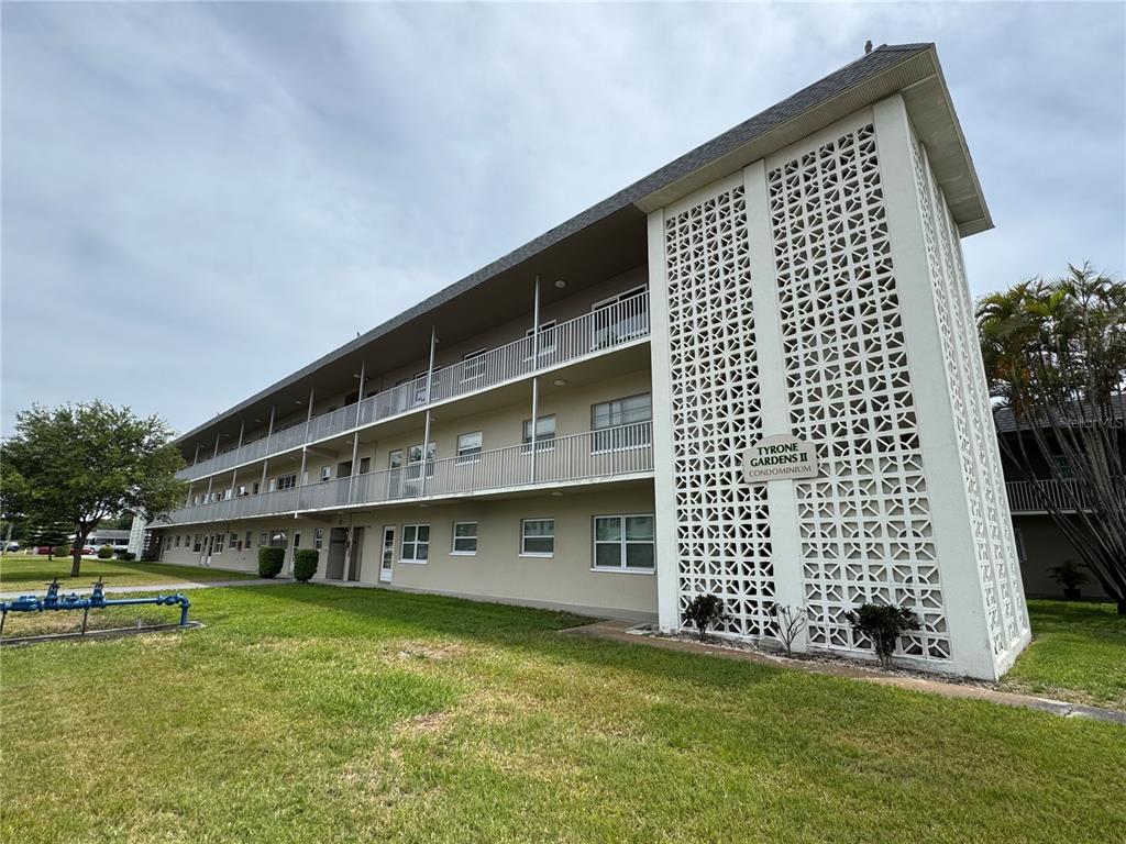 A three-story apartment building features a decorative concrete block screen wall and exterior walkways — 5720 13TH AVENUE N UNIT 106B, ST PETERSBURG, FL