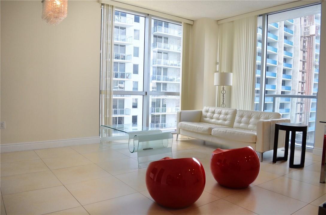 A modern living room features a white sofa, red spherical chairs, and floor-to-ceiling windows — 1060 Brickell Avenue # 1617, Miami FL 33131, MIAMI, FL