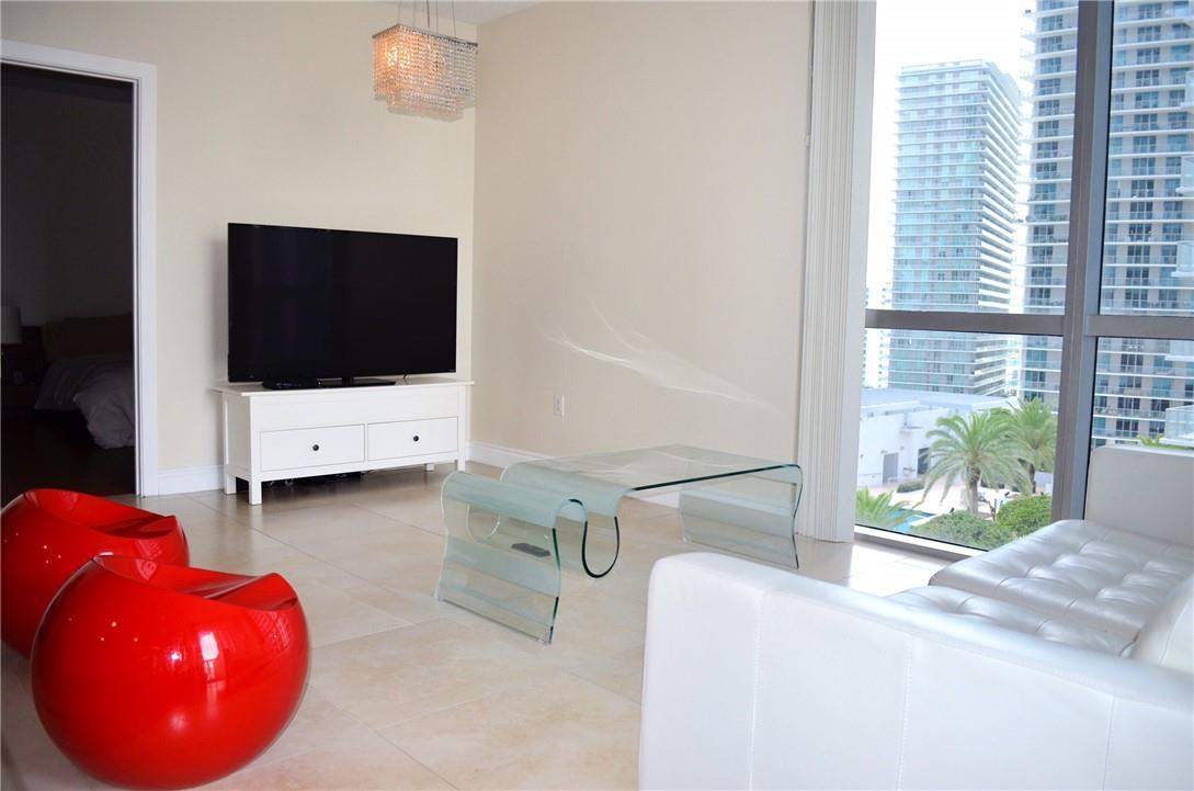 A modern living room features red spherical chairs, a glass coffee table, and city views — 1060 Brickell Avenue # 1617, Miami FL 33131, MIAMI, FL