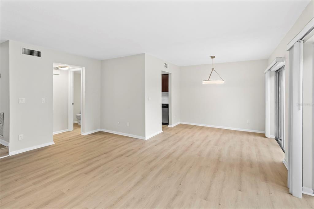 An open-concept living and dining area features light wood-look flooring and a modern pendant light — 6226 GOLDENMOSS WAY UNIT 6226, TAMPA, FL