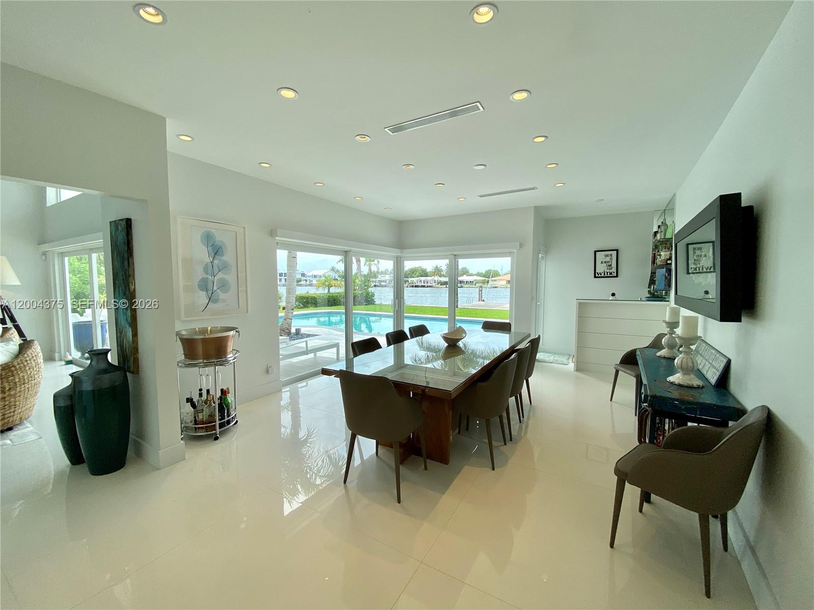 A dining room with a glass table, tile floors, and large windows overlooking a pool — 265 N Shore Dr, Miami Beach FL 33141, MIAMI BEACH, FL
