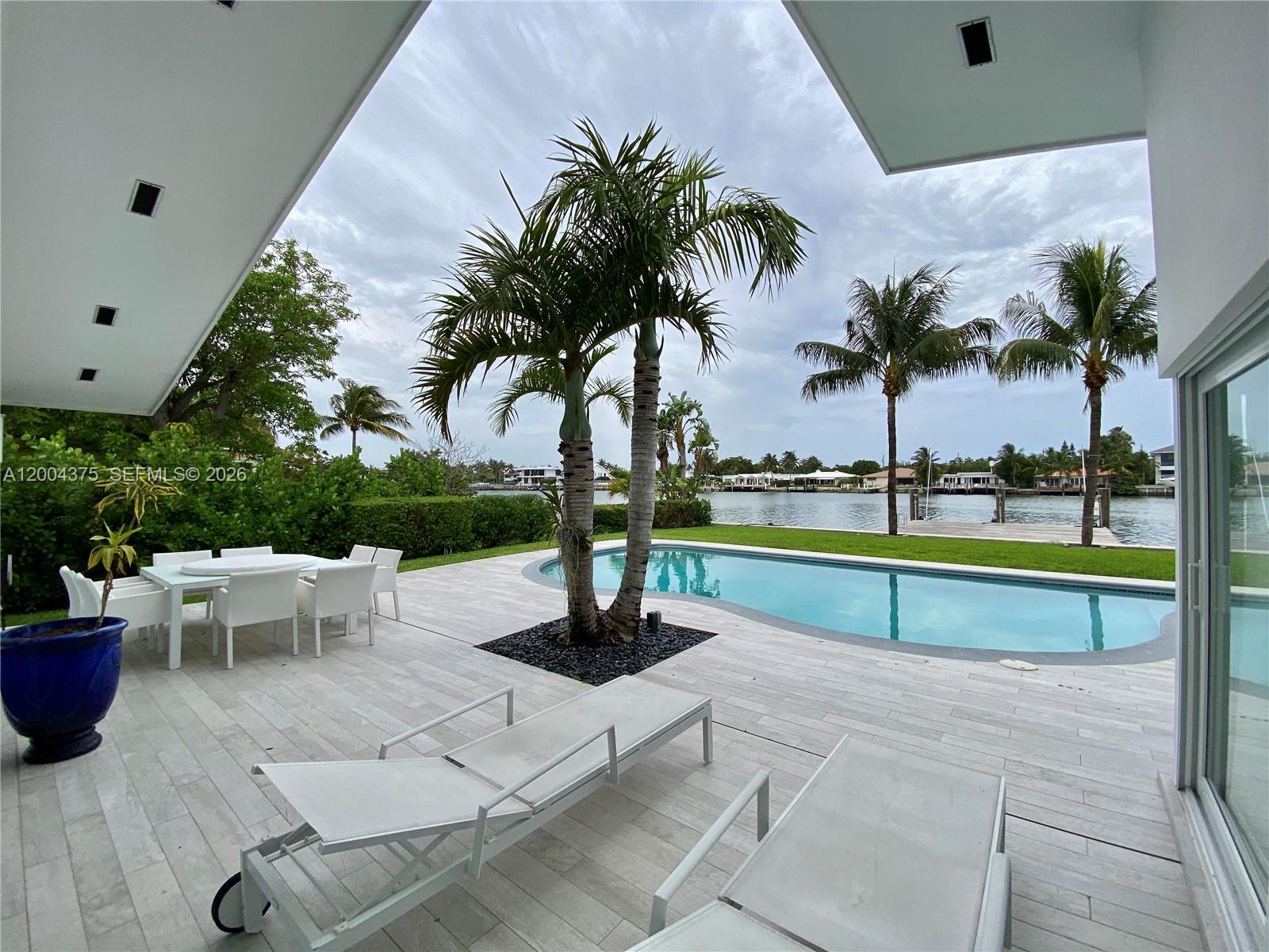 A patio with a swimming pool, lounge chairs, and dining set overlooks a waterfront canal — 265 N Shore Dr, Miami Beach FL 33141, MIAMI BEACH, FL
