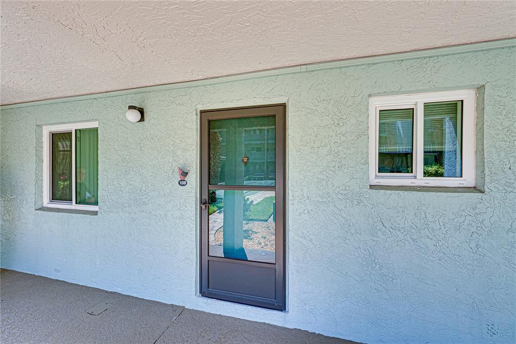 A light blue stucco exterior wall features a front door and two sliding windows — 801 83RD AVENUE N UNIT 108, ST PETERSBURG, FL