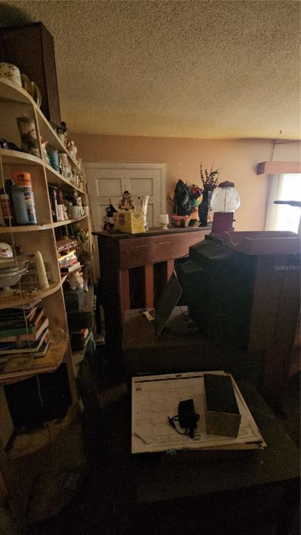 A cluttered room features a tall wooden shelving unit, a desk, and a calendar — 2116 WINNETKA COURT, ORLANDO, FL