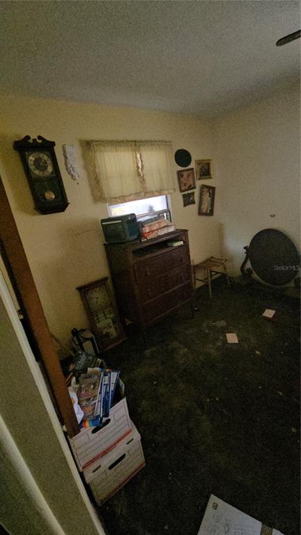 A small room with a wooden dresser, wall-mounted clock, window, and dark flooring — 2116 WINNETKA COURT, ORLANDO, FL
