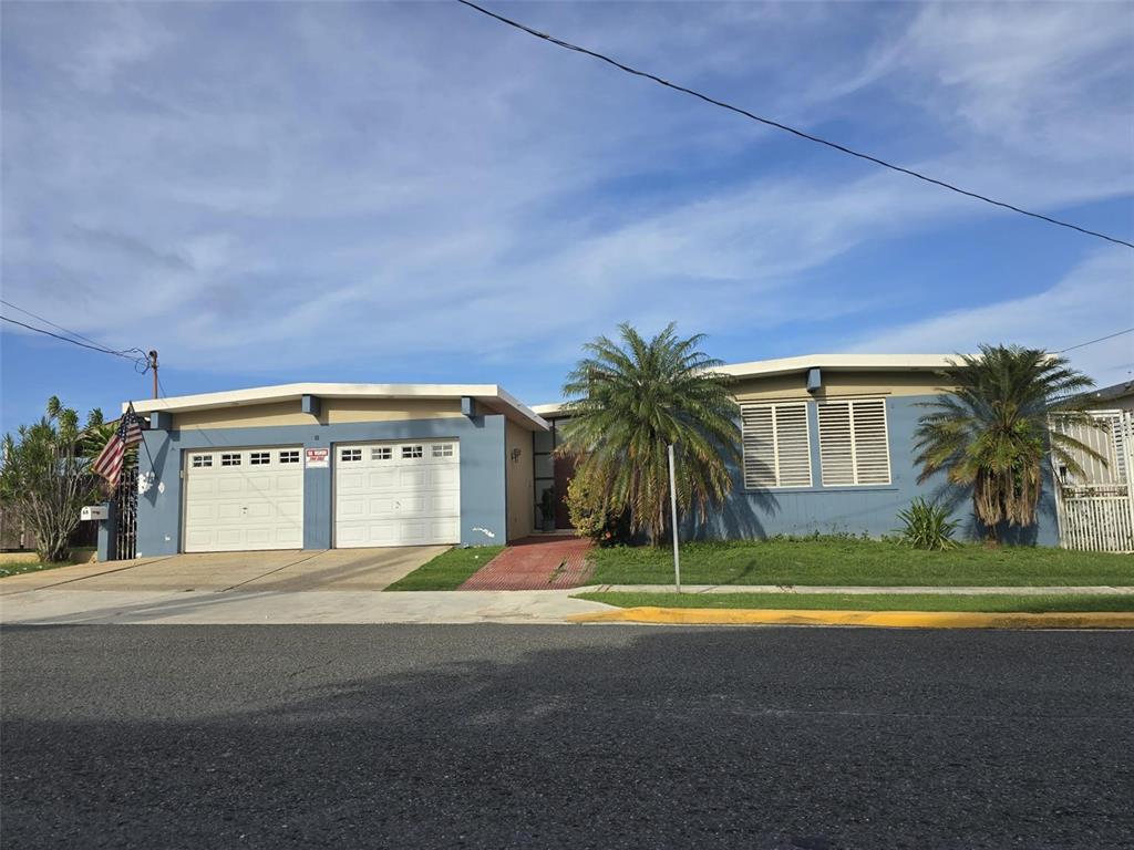 A single-story blue house with a two-car garage and two palm trees in the front — 68 SOCORRO STREET, QUEBRADILLAS, PR