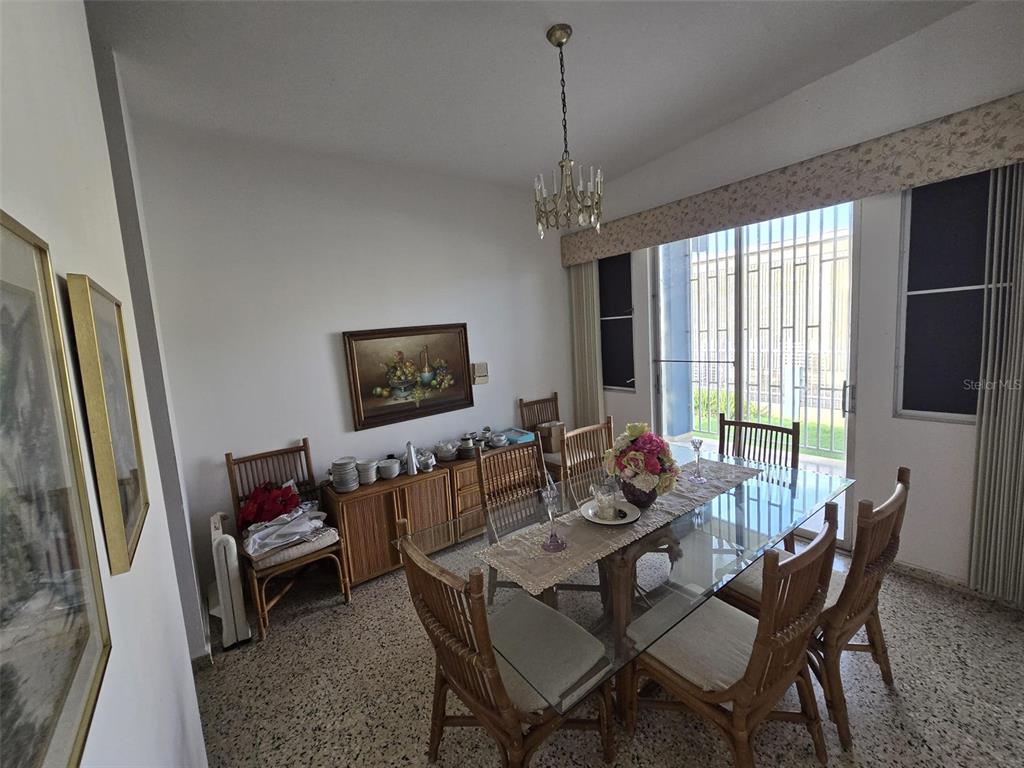 A dining room features a glass-topped table, wicker chairs, a sideboard, and a chandelier — 68 SOCORRO STREET, QUEBRADILLAS, PR