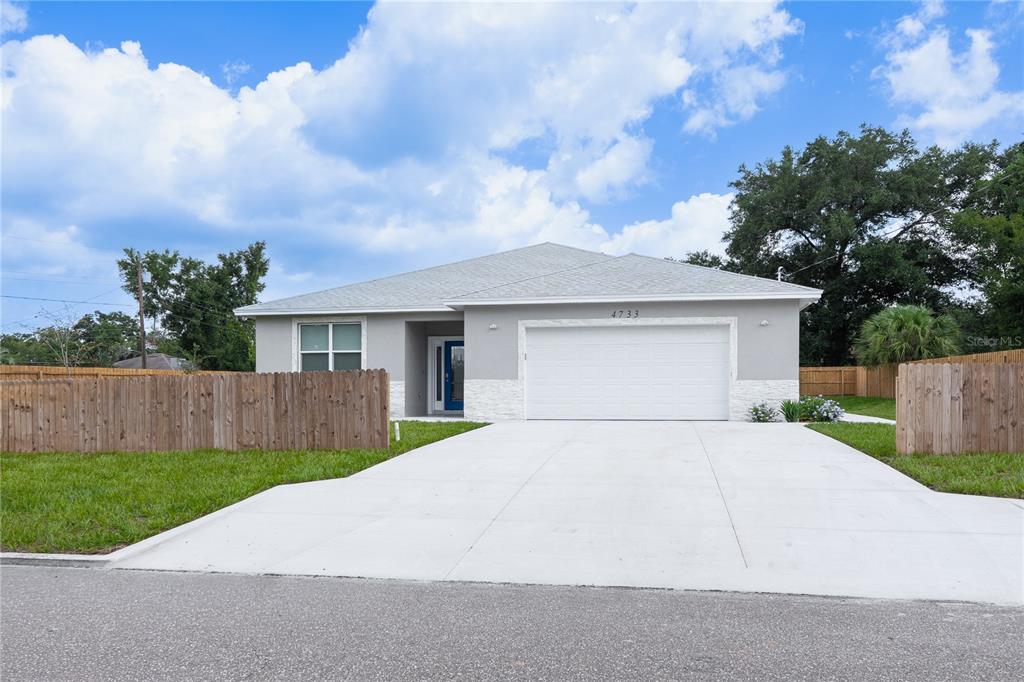 A single-story house with a white garage, gray exterior, and a wooden fence — 4733 ABACA STREET, ORLANDO, FL