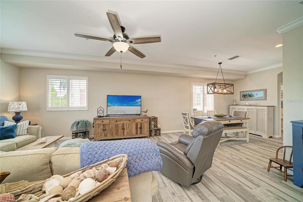 A living and dining area features light wood-look tile flooring, a ceiling fan, and furniture — 3607 10TH LANE W, PALMETTO, FL
