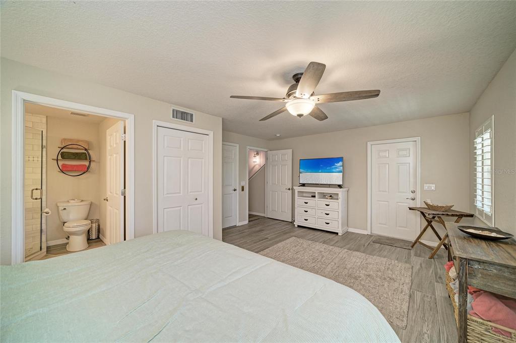 A bedroom with light wood-look flooring, a ceiling fan, a dresser, and an attached bathroom — 3607 10TH LANE W, PALMETTO, FL