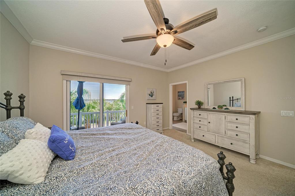 A bedroom features a king bed, white dresser, ceiling fan, and sliding doors to a balcony — 3607 10TH LANE W, PALMETTO, FL