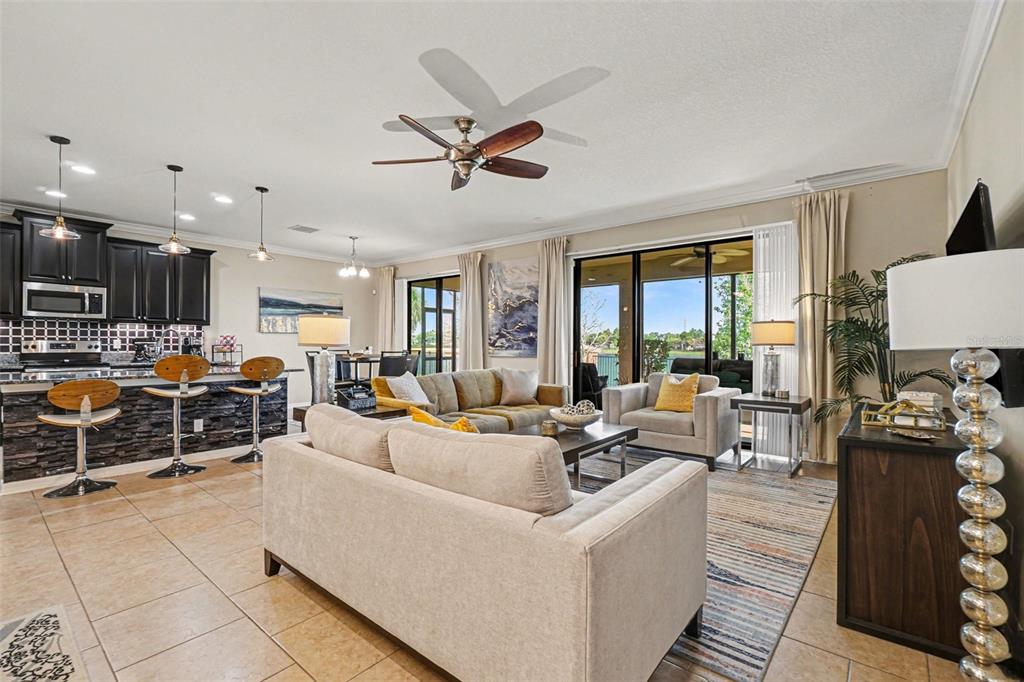 An open-concept living room and kitchen featuring tile floors, dark cabinetry, and sliding glass doors — 11428 CARLTON FIELDS DRIVE, RIVERVIEW, FL
