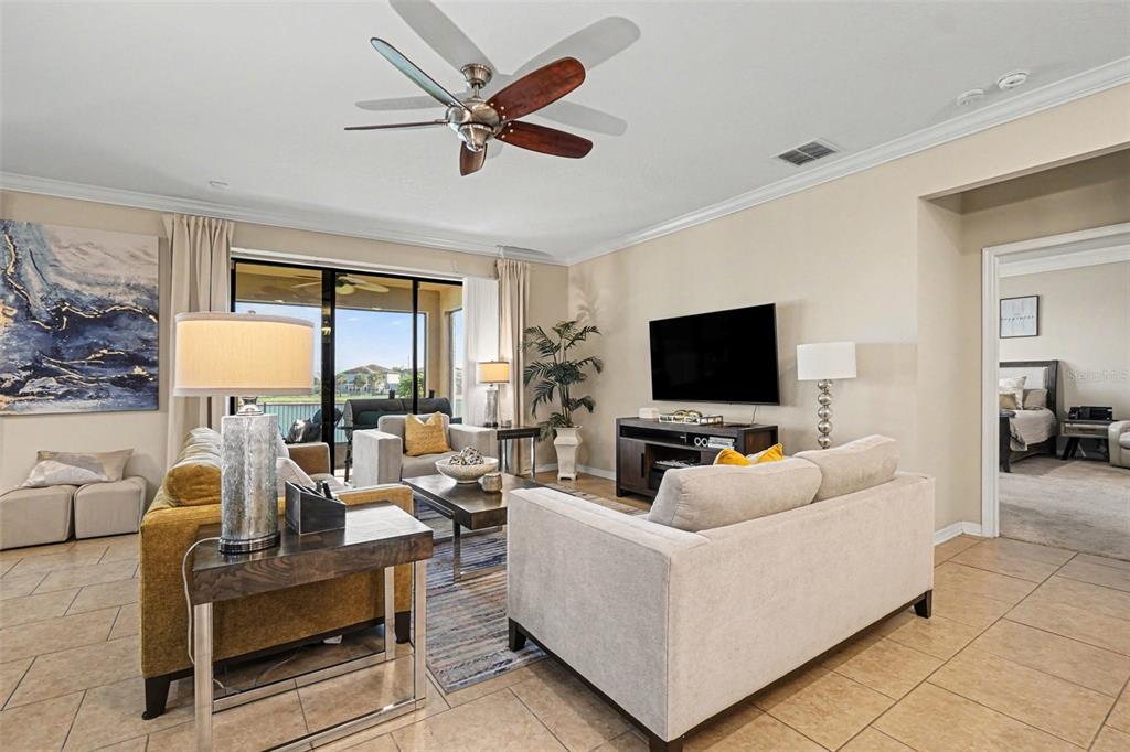 A screened-in patio features dark blue outdoor furniture, ceiling fans, and a view of water — 11428 CARLTON FIELDS DRIVE, RIVERVIEW, FL