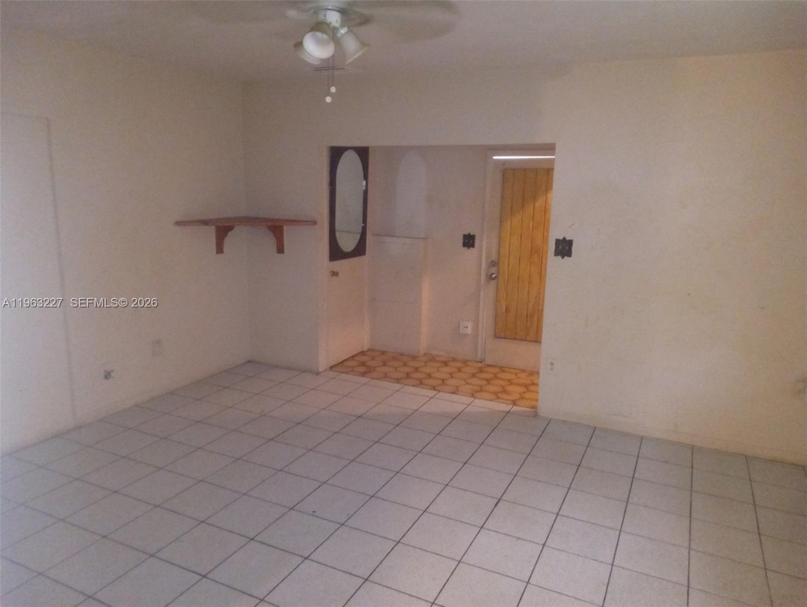 An interior room features white tiled floors, a ceiling fan, and a wooden door — 1925 Harding St # D, Hollywood FL 33020, HOLLYWOOD, FL