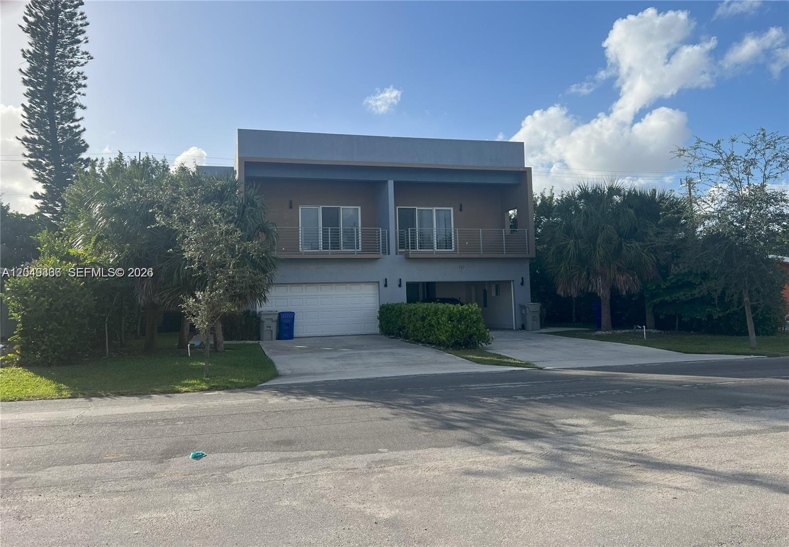 A two-story duplex features a concrete driveway, a garage, and an upper-level balcony — 1121 NE 23rd Ter # 1121, Pompano Beach FL 33062, POMPANO BEACH, FL