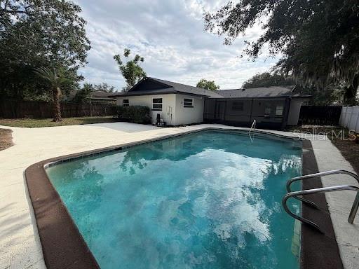 A backyard swimming pool sits in front of a single-story house with a screened porch — 1803 BALSAWOOD COURT, ORLANDO, FL
