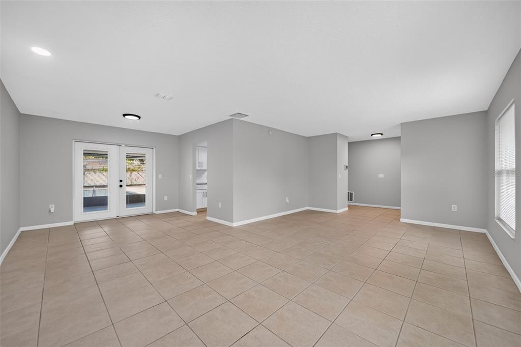 An empty room with gray walls, tile flooring, and glass French doors leading outside — 1803 BALSAWOOD COURT, ORLANDO, FL
