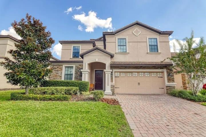 A two-story house with a beige stucco exterior, stone accents, and a paved driveway — 1455 BELLE TERRE ROAD, DAVENPORT, FL