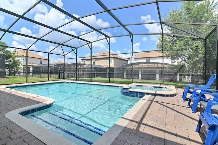 A screened-in swimming pool and spa with blue lounge chairs on a brick patio — 1455 BELLE TERRE ROAD, DAVENPORT, FL