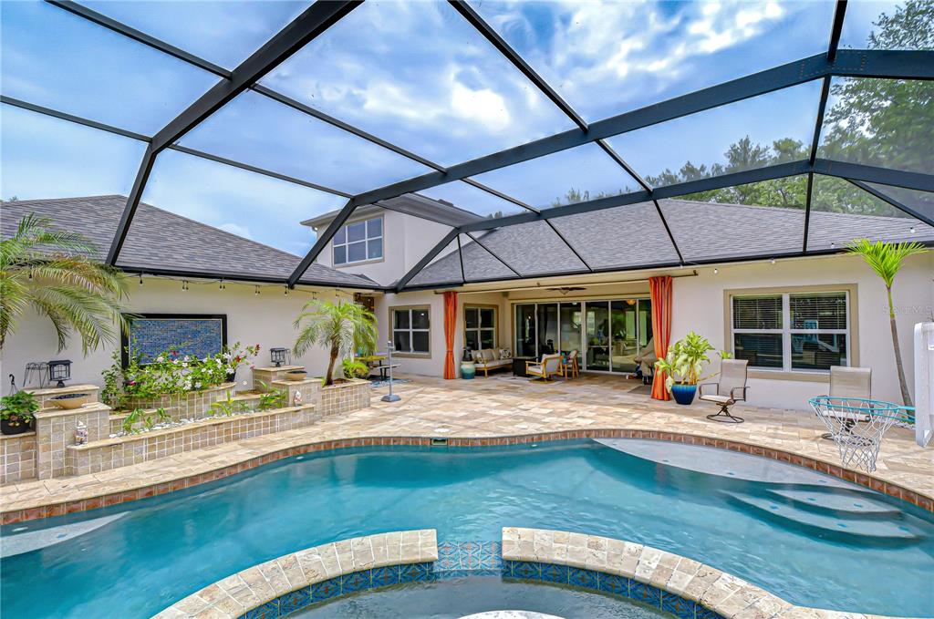 A screened-in patio features a swimming pool, a raised planter, and stone paver flooring — 5907 CHURCHSIDE DRIVE, LITHIA, FL