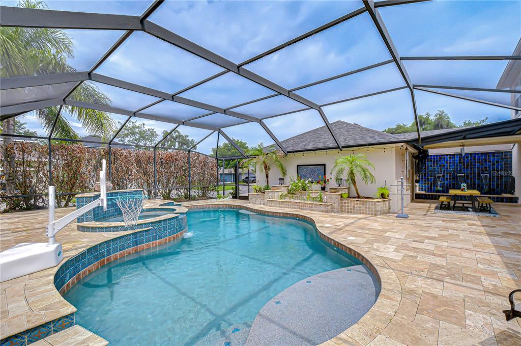 A screened-in swimming pool and spa with a stone patio and a blue tiled wall — 5907 CHURCHSIDE DRIVE, LITHIA, FL