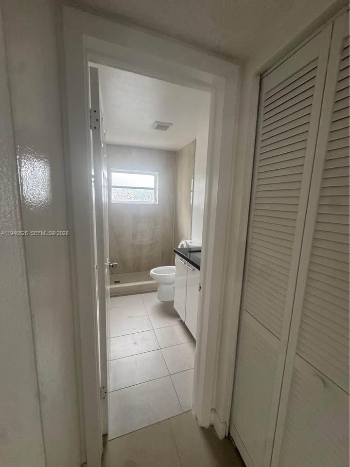 A view through a doorway into a bathroom with a toilet and a shower stall — 2019 Jackson St # 105, Hollywood FL 33020, HOLLYWOOD, FL
