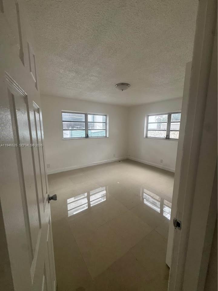 An empty bedroom with white walls, tiled floors, and two windows — 2019 Jackson St # 105, Hollywood FL 33020, HOLLYWOOD, FL