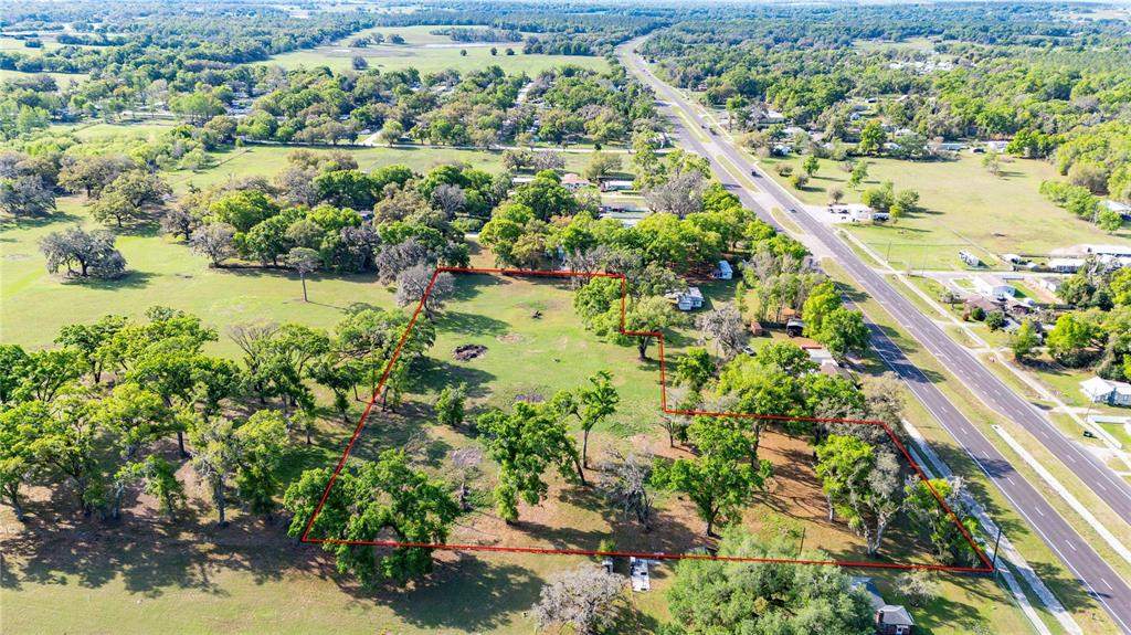 An aerial view shows a large, grassy, tree-dotted plot of land outlined in red — 0 US HIGHWAY 301 N, DADE CITY, FL