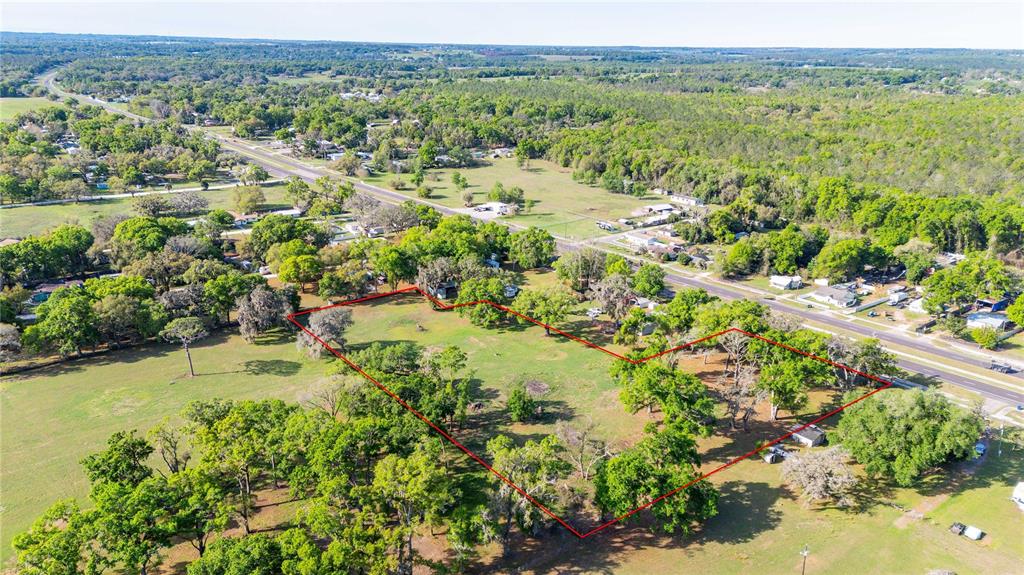An aerial view shows a large, grassy, tree-dotted plot of land outlined in red — 0 US HIGHWAY 301 N, DADE CITY, FL