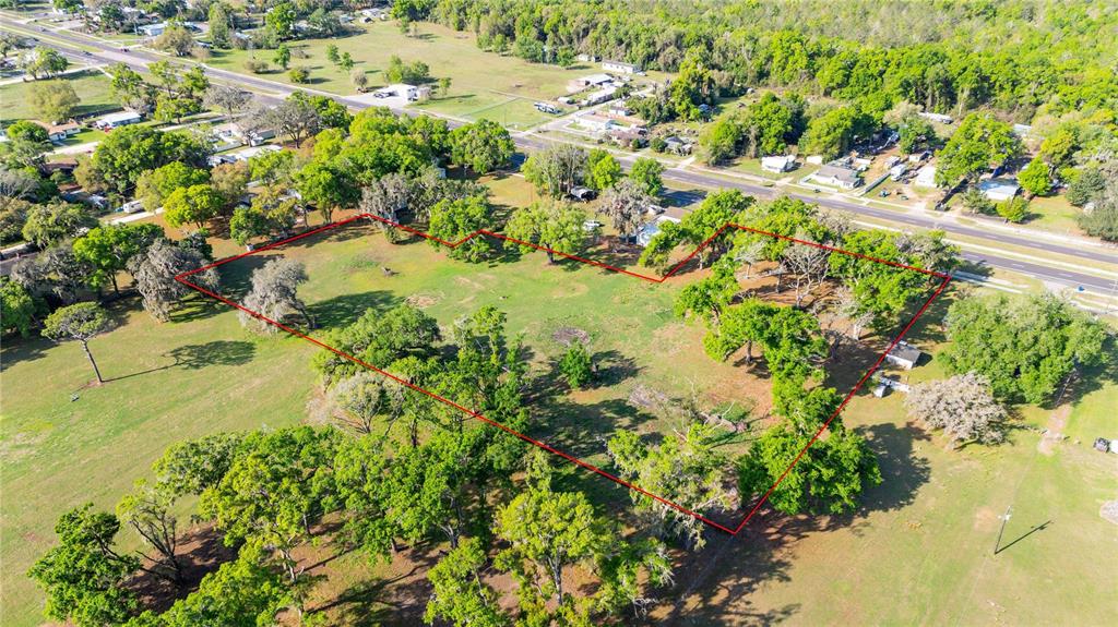 An aerial view shows a large, grassy, tree-filled plot of land outlined in red — 0 US HIGHWAY 301 N, DADE CITY, FL