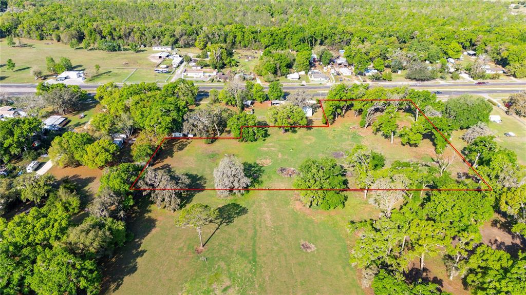 An aerial view shows a large, grassy, tree-filled lot outlined in red — 0 US HIGHWAY 301 N, DADE CITY, FL
