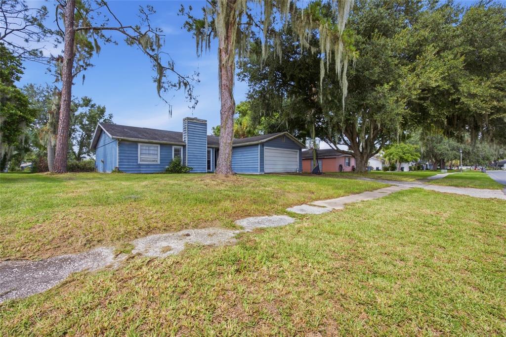A blue single-story house with a chimney and attached garage sits on a grassy lot — 3135 CROSS FOX DRIVE, MULBERRY, FL