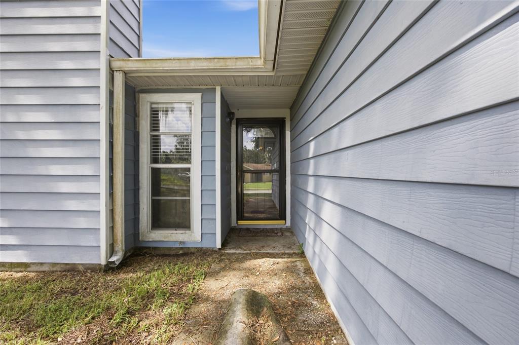 A blue-sided house exterior features a front door with a storm door and a window — 3135 CROSS FOX DRIVE, MULBERRY, FL
