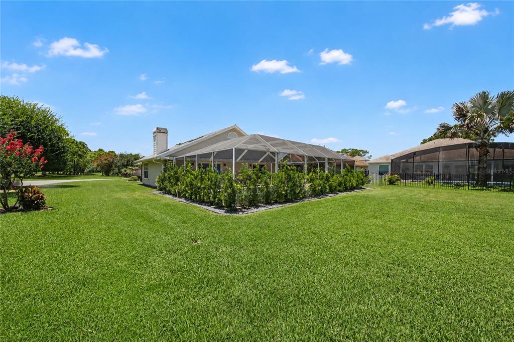 A backyard view of a house with a screened-in pool enclosure and a grassy lawn — 2013 BEAVER CREEK DRIVE, PORT ORANGE, FL