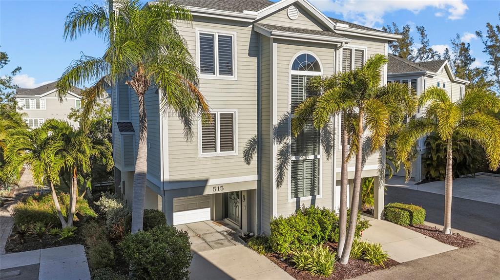 A three-story light green house with a garage, palm trees, and a paved driveway — 515 FOREST WAY, LONGBOAT KEY, FL