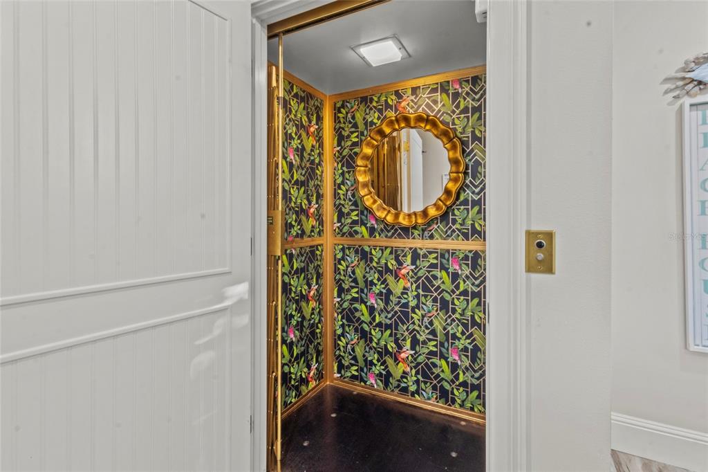 An elevator interior features dark floral wallpaper, a gold-framed mirror, and a black floor — 515 FOREST WAY, LONGBOAT KEY, FL