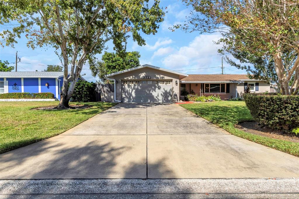 A single-story house with a concrete driveway, a two-car garage, and mature trees — 1773 63RD AVENUE S, ST PETERSBURG, FL
