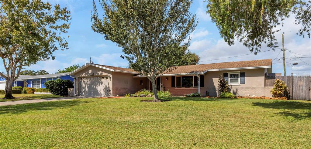 A single-story ranch-style house with a tan exterior, a two-car garage, and a large lawn — 1773 63RD AVENUE S, ST PETERSBURG, FL